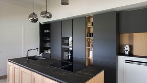Una cocina moderna con una isla central, muebles oscuros y electrodomésticos integrados.