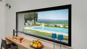 Una habitación moderna con un ventanal grande con vistas a una piscina y al paisaje.