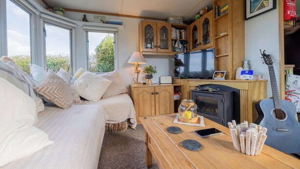 Une pièce confortable avec un lit, une table en bois, une télévision et une guitare.