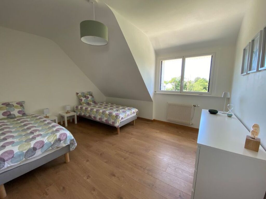 Une chambre avec deux lits, un bureau, un radiateur et une fenêtre.