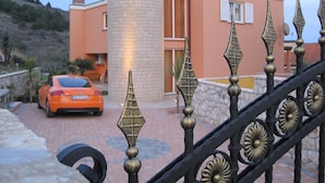 A modern building with a cylindrical tower, a car parked in front, and a decorative metal fence. - 4-Star Comfort Apartment with Ocean View, Rabac, Croatia (Rabac)