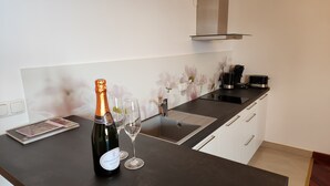 A modern kitchen with a black countertop, a bottle of champagne, and two glasses. - 4-Star Comfort Apartment with Ocean View, Rabac, Croatia (Rabac)
