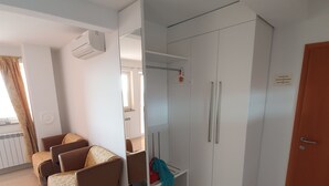 A modern room with a sofa, wardrobe, and a small table. - 4-Star Comfort Apartment with Ocean View, Rabac, Croatia (Rabac)