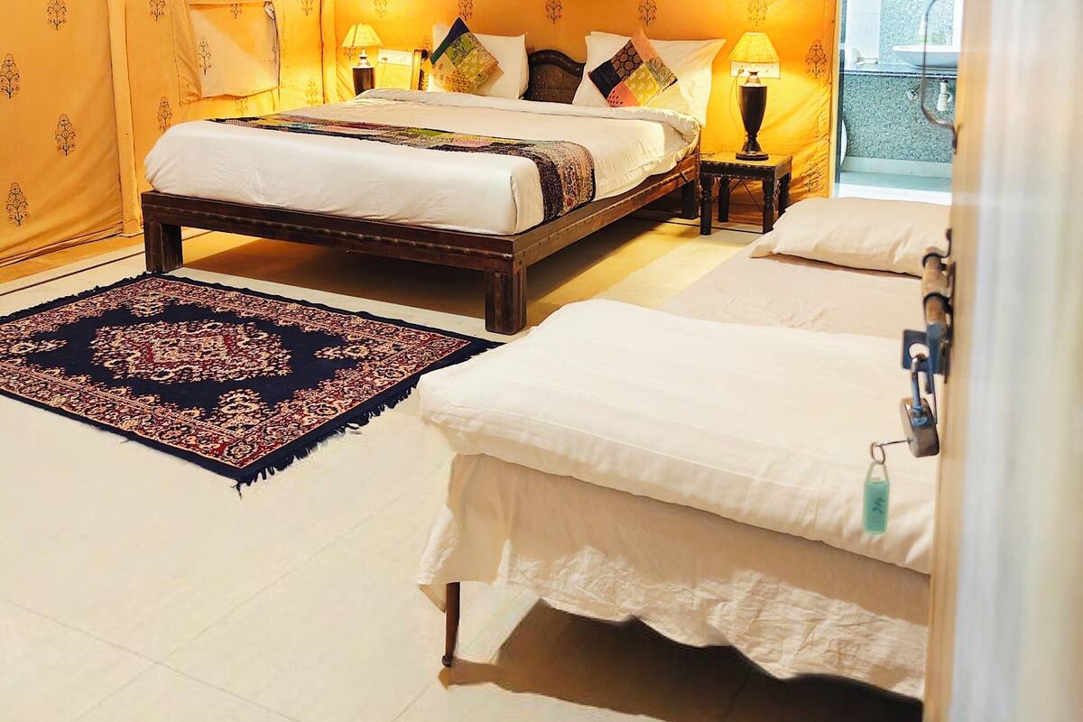A tent-style room with a bed, bedside table, and a rug.