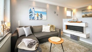 Ein modernes Wohnzimmer mit einem grauen Sofa, einem kleinen runden Tisch und Kunstwerken mit Surfbrettern.