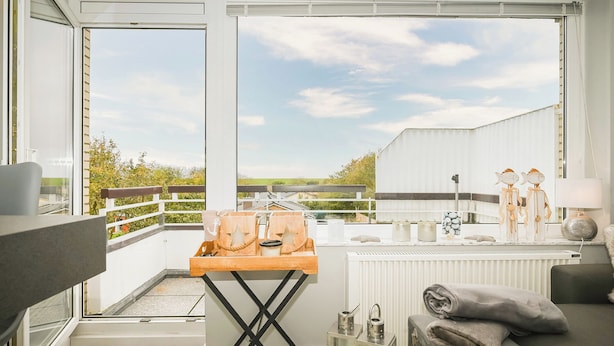 Ein Balkon mit einem Holztisch, einem Heizkörper und einer Couch mit Kissen.