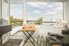 Un balcon avec une table en bois, un radiateur et un canapé avec des coussins.