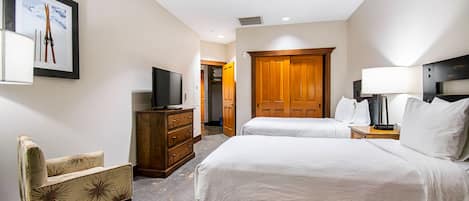 A hotel room with a bed, a television on a dresser, a chair, and a wooden door.