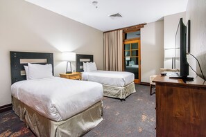 Une chambre d’hôtel avec deux lits, un bureau, une télévision et une fenêtre avec des rideaux.