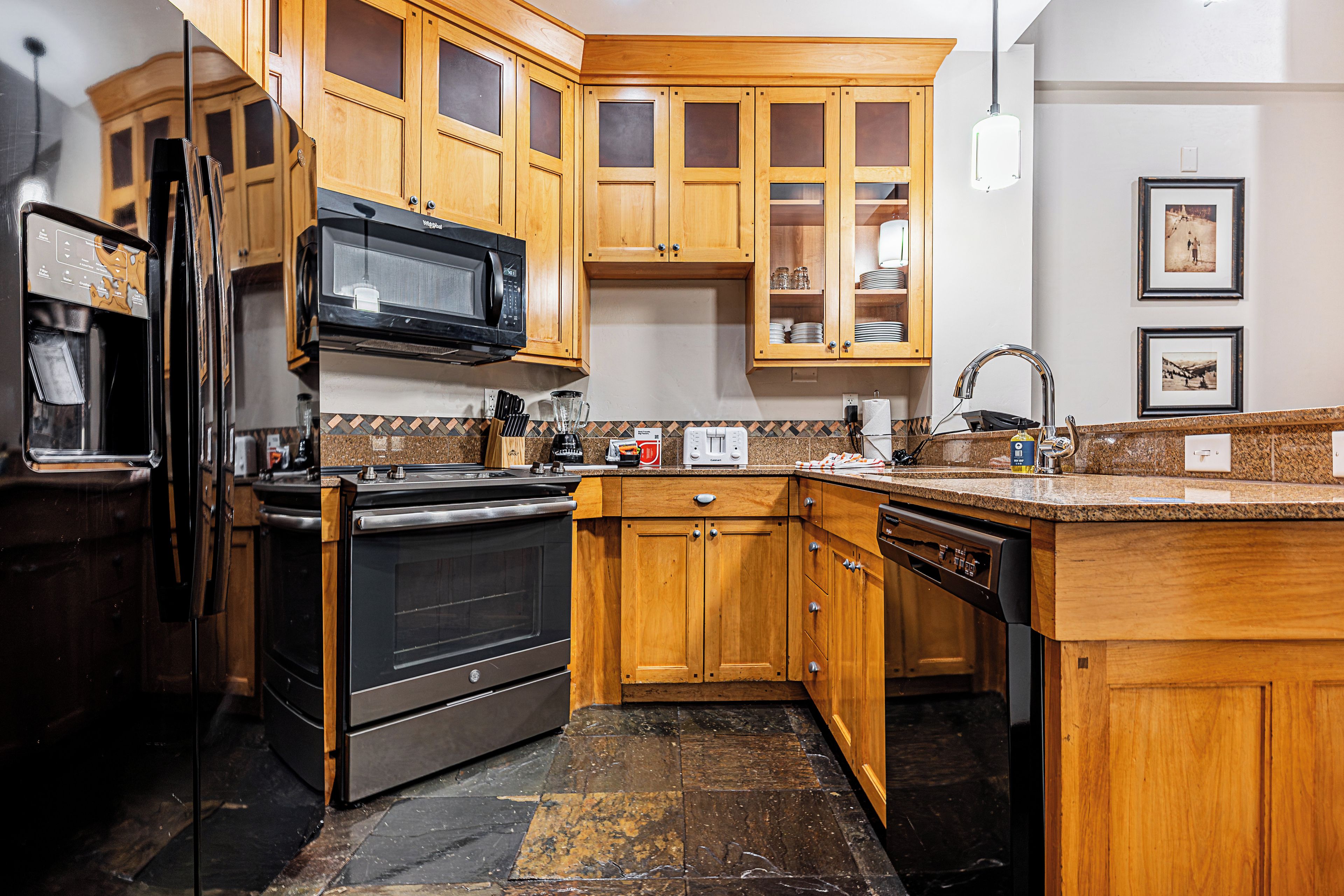 A kitchen with wooden cabinets, a black refrigerator, a stove, a microwave, and a dishwasher.