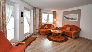 A modern living room with a sofa set, a coffee table, and a chair. - Küstenwind: Cozy 2-room apartment with use of swimming pool (Büsum)