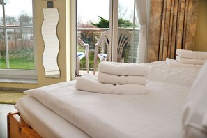 A hotel room with a bed, a chair, and a view of the outdoors. - Küstenwind: Cozy 2-room apartment with pool access (Büsum)