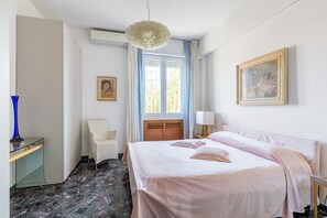 Una habitación de hotel con cama, una silla, un escritorio y un ventanal con cortinas.