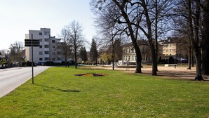 A park with a grassy area, trees, and a building in the background. - ME LIVING 1: Hauptallee - Bad Pyrmont - Apartment (Bad Pyrmont)