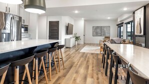 Una cuina moderna amb una illa central, tamborets i una zona de menjador amb cadires.