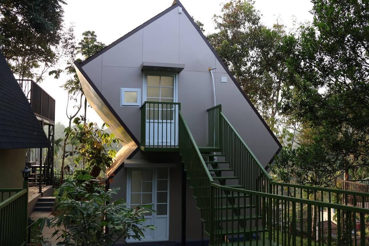 Una casa moderna dal design angolare originale, con un piccolo balcone e una scala che conduce all'ingresso.