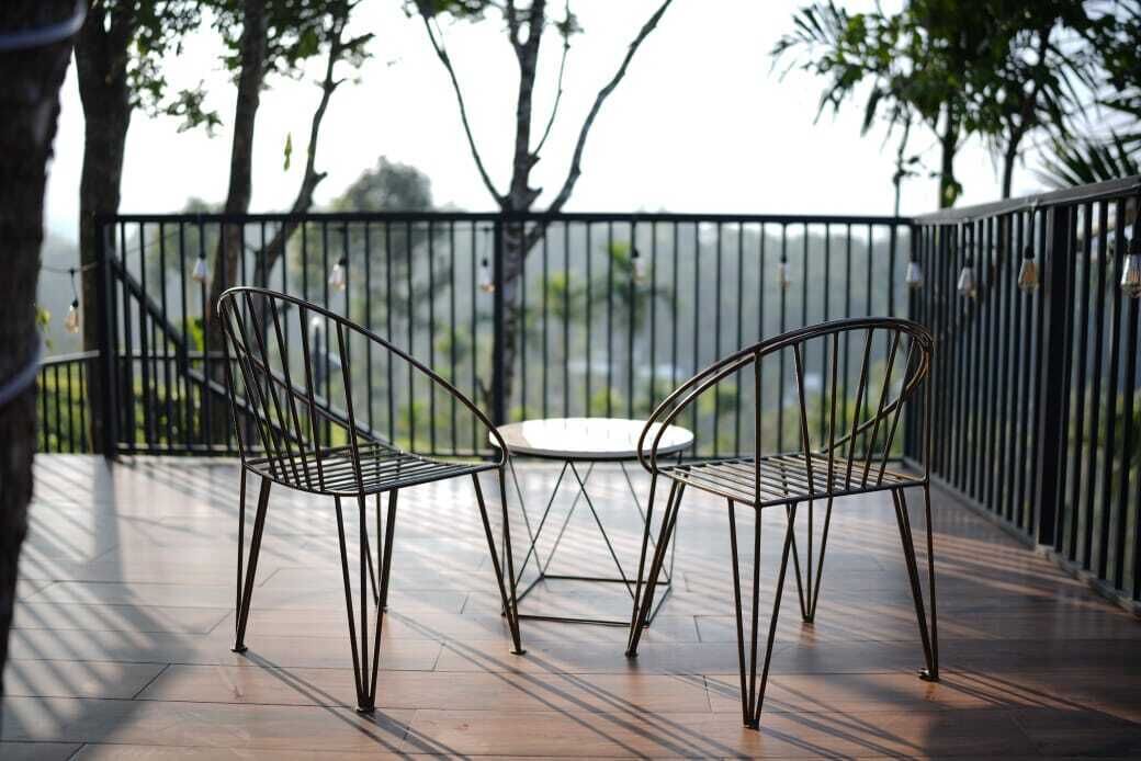 Een balkon met twee metalen stoelen en een kleine ronde tafel, met uitzicht op een schilderachtig panorama.