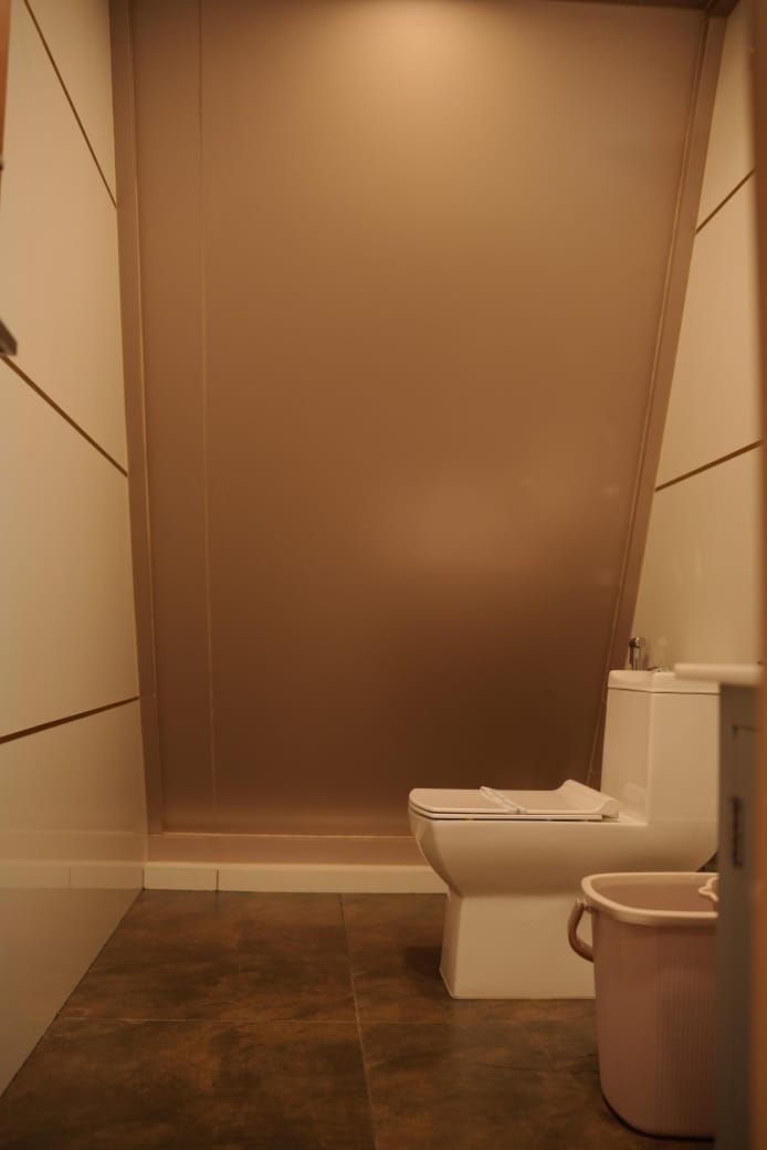 Un baño pequeño y cerrado con un inodoro y un cubo de basura.