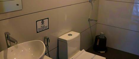 A bathroom with a sink, toilet, and shower. A sign instructs to use disposable sanitary napkins or diapers.