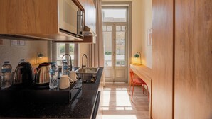 A compact kitchen with a sink, stove, and various appliances. A window with curtains is visible in the background. - Brassbell Zamalek Daoud Studios Villa A (Cairo)