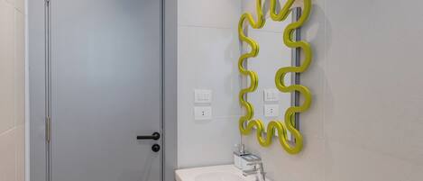 A bathroom with a white sink, a mirror with a yellow frame, and a door.