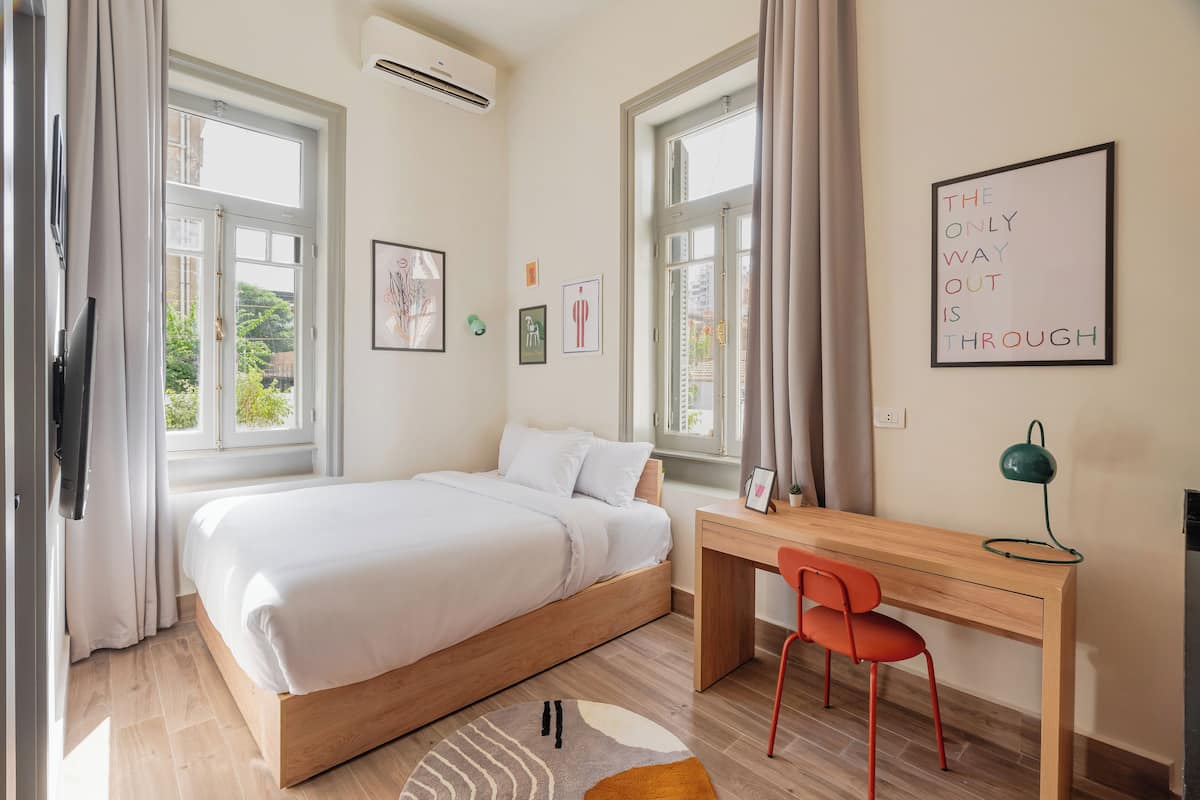 A bedroom with a bed, a desk, a chair, and a wall with a motivational quote.