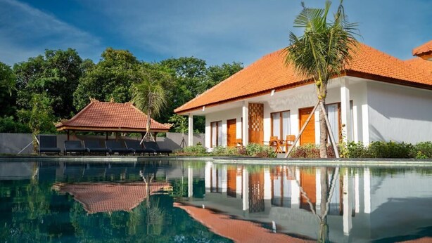 Ein Pool mit klarem Wasser, das die umliegenden Gebäude und Bäume reflektiert.