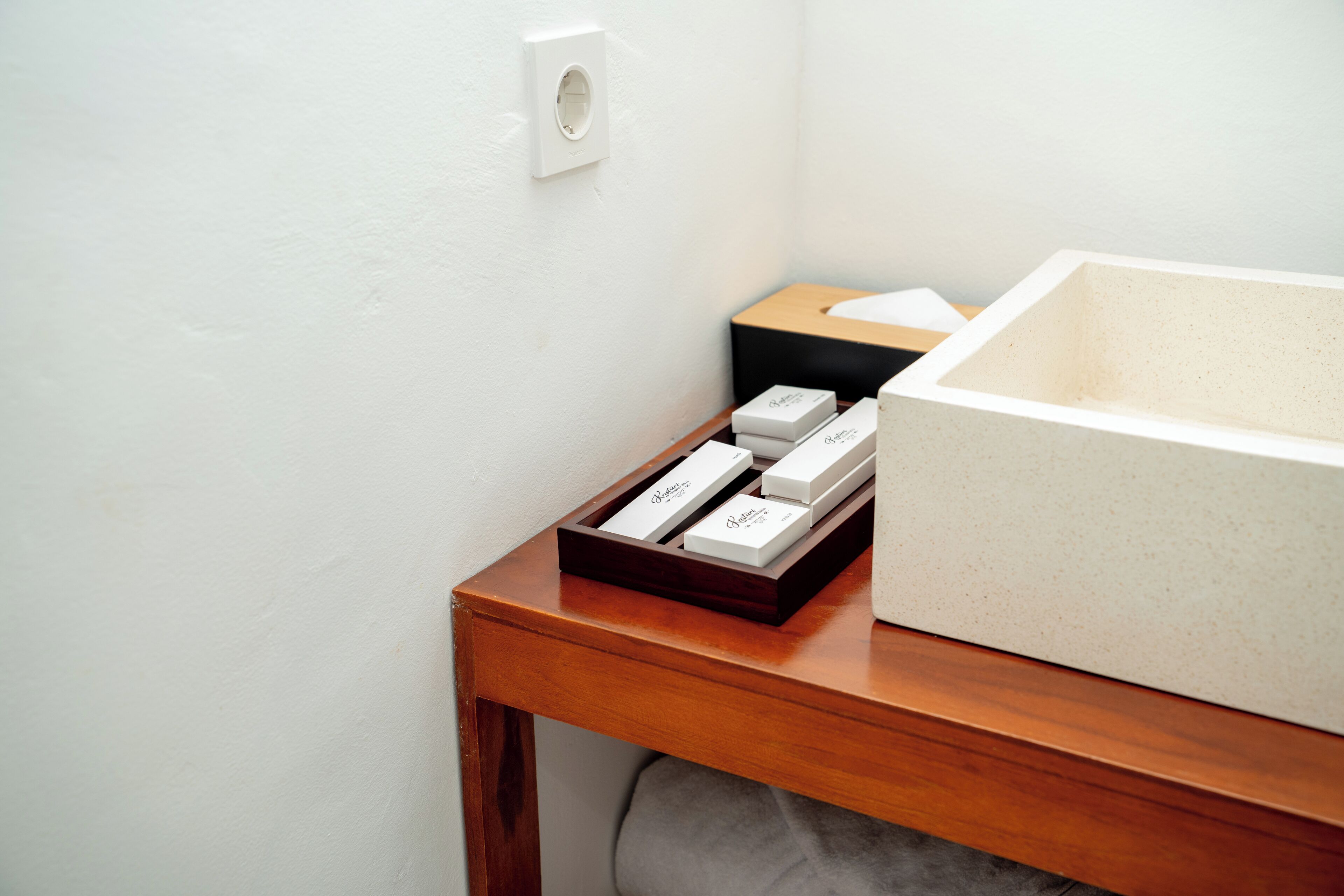 Un baño con tocador de madera, un lavabo blanco y una caja de pañuelos en la encimera.