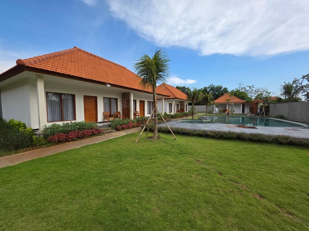 A residential property with a swimming pool, a well-maintained lawn, and a red-tiled roof.