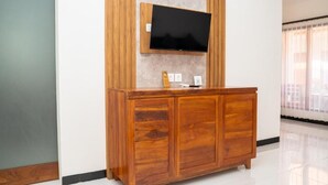 Ein Holzkabinett mit einem flachbildfernseher darüber, ein kleiner Tisch und eine Steckdose.