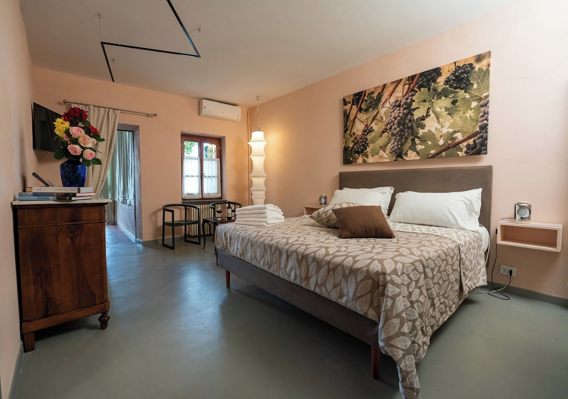 A bedroom with a large bed, a desk, a chair, a TV, and a painting on the wall.