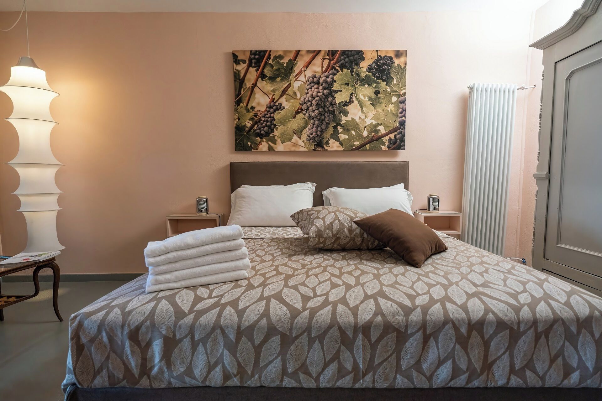 Un lit bien fait, avec une couvre-lit à motifs, deux oreillers et des serviettes pliées posées sur la tête de lit.