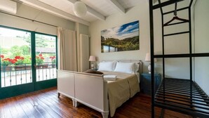 Une chambre à coucher avec un lit, des tables de chevet, un luminaire suspendu, une fenêtre avec des rideaux et un tableau au mur.