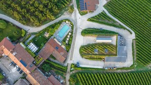 Vue aérienne d’un quartier résidentiel avec une piscine, des panneaux solaires et un grand bâtiment doté d’un toit en pente.