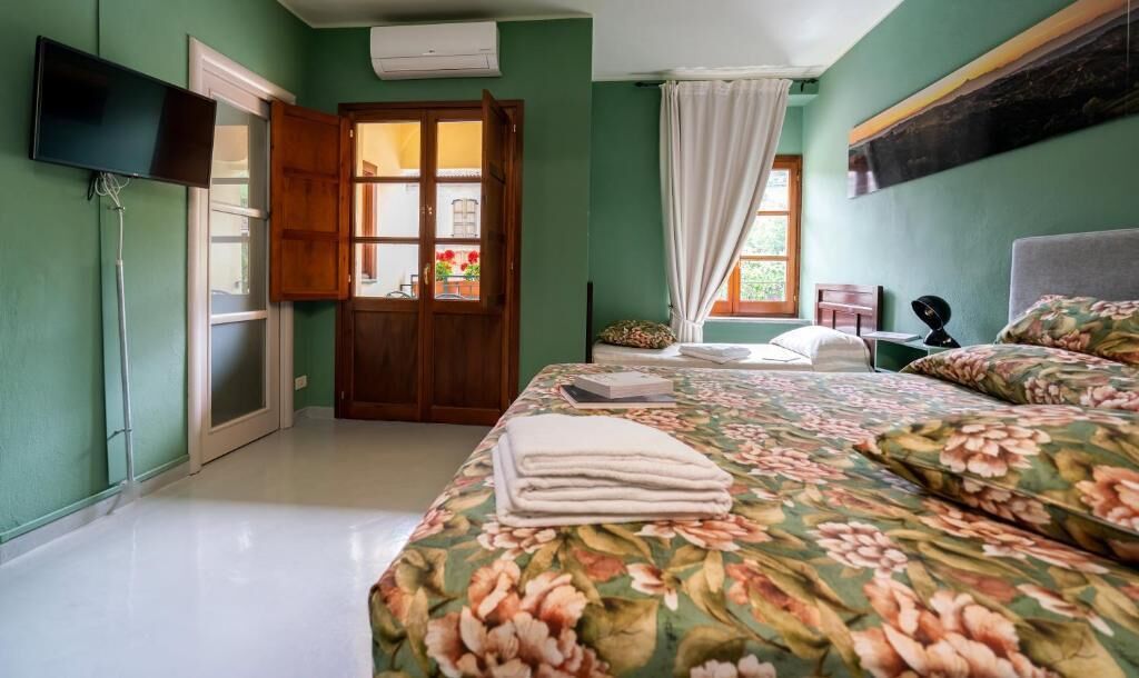 Ein Schlafzimmer mit Bett, Fernseher, Kleiderschrank und einem Fenster mit Vorhängen.