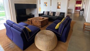A spacious living room with a large TV, two blue sofas, a wooden coffee table, and a woven ottoman. - Alamo da Serra (Freixo)