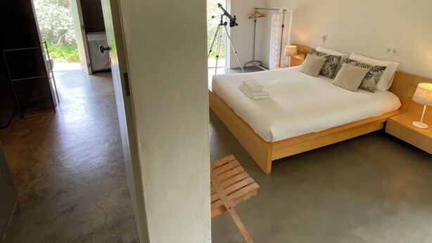 A modern bedroom with a large bed, a bedside table with a lamp, and a telescope. - Alamo da Serra (Freixo)