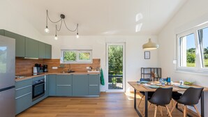 Eine moderne Küche mit grauen Schränken, einer Holzarbeitsplatte und einem Essbereich mit Tisch und Stühlen.