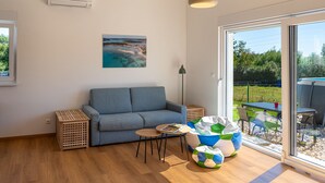 Ein modernes Wohnzimmer mit einem grauen Sofa, einem kleinen runden Tisch und einer bunten Kinderspielecke.
