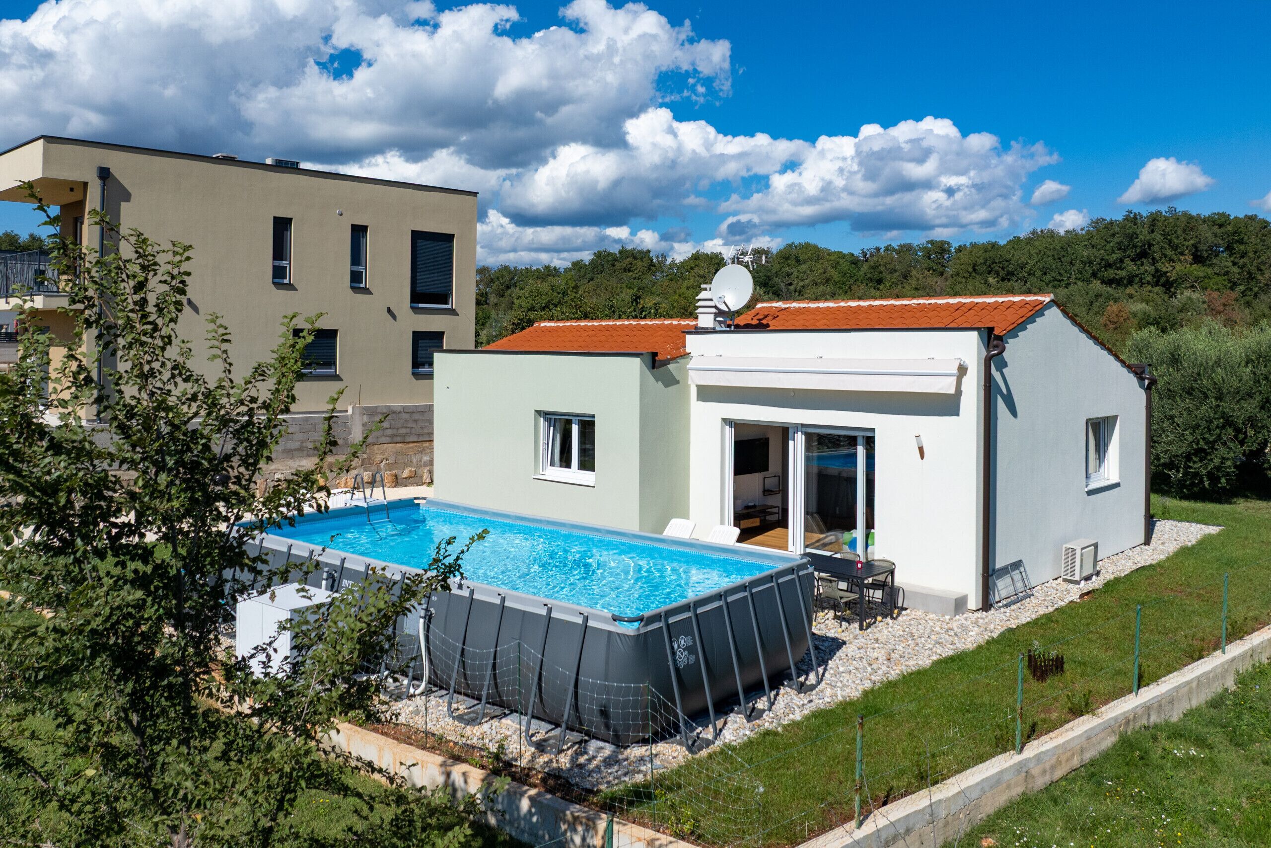 Ein modernes Haus mit Swimmingpool, Satellitenschüssel und einem roten Dach.