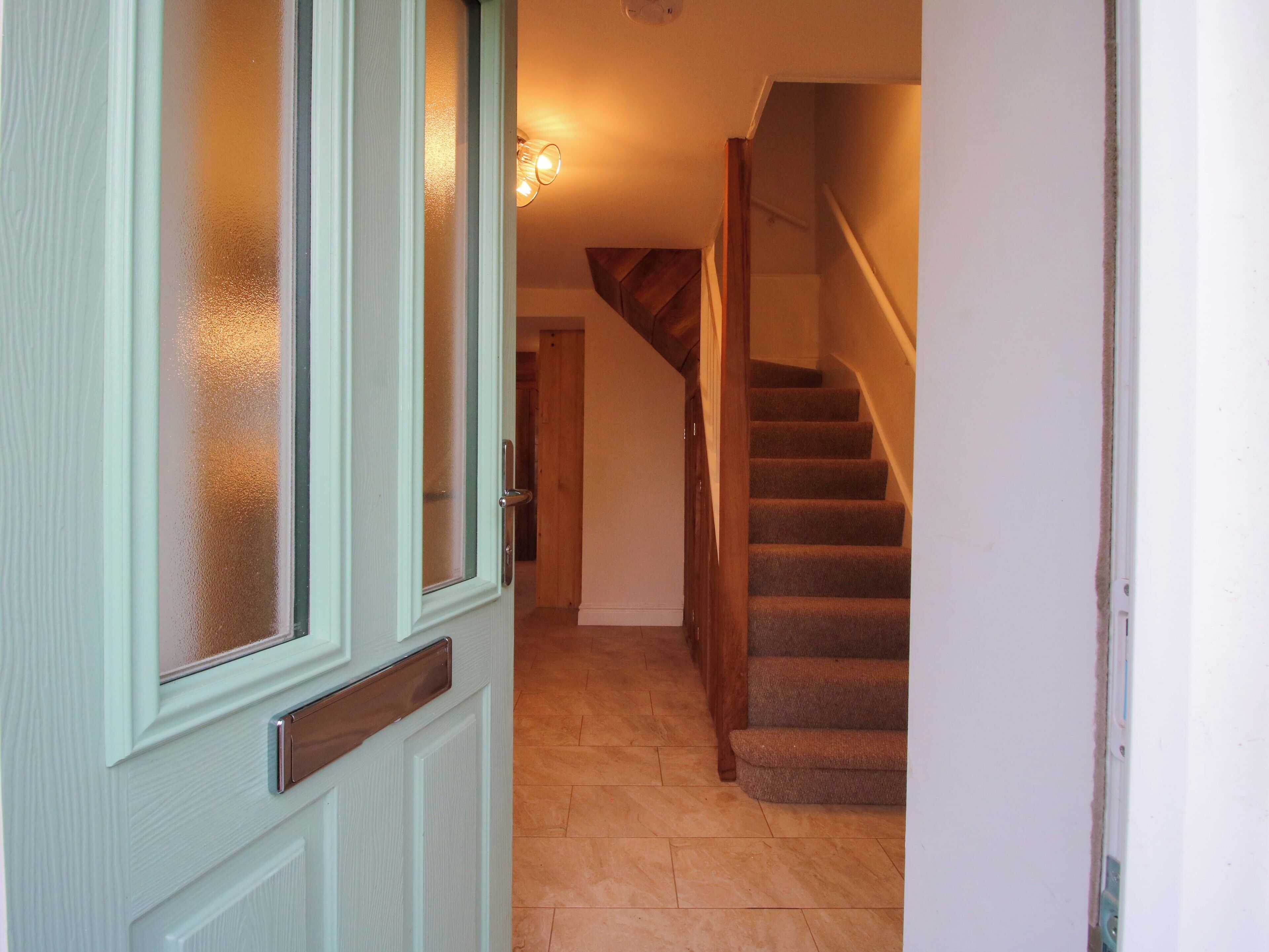 Un pasillo con una escalera de madera y una puerta con paneles de vidrio esmerilado.