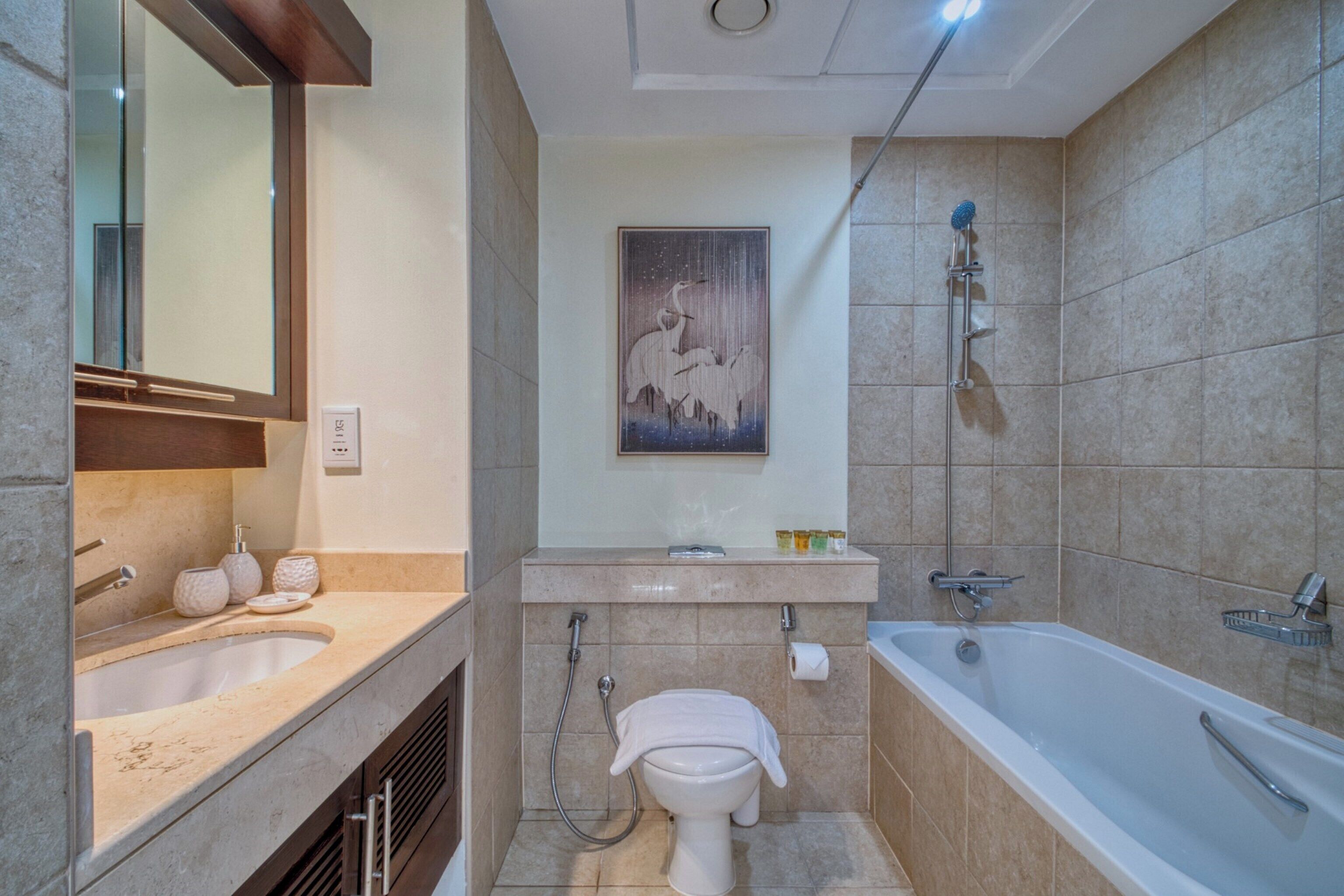 A modern bathroom with a sink, toilet, and bathtub.