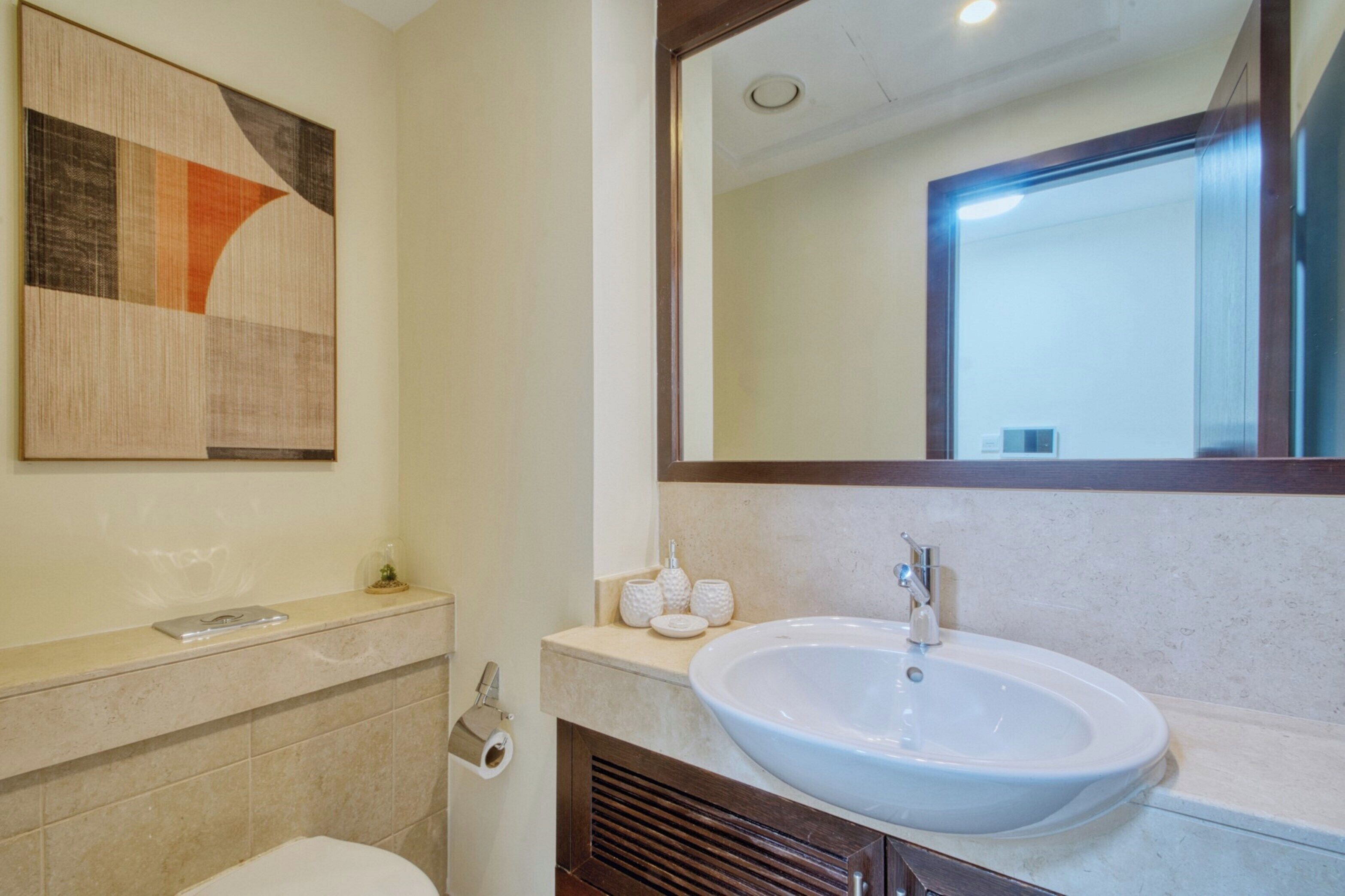 A bathroom with a large mirror, a sink, and a toilet.
