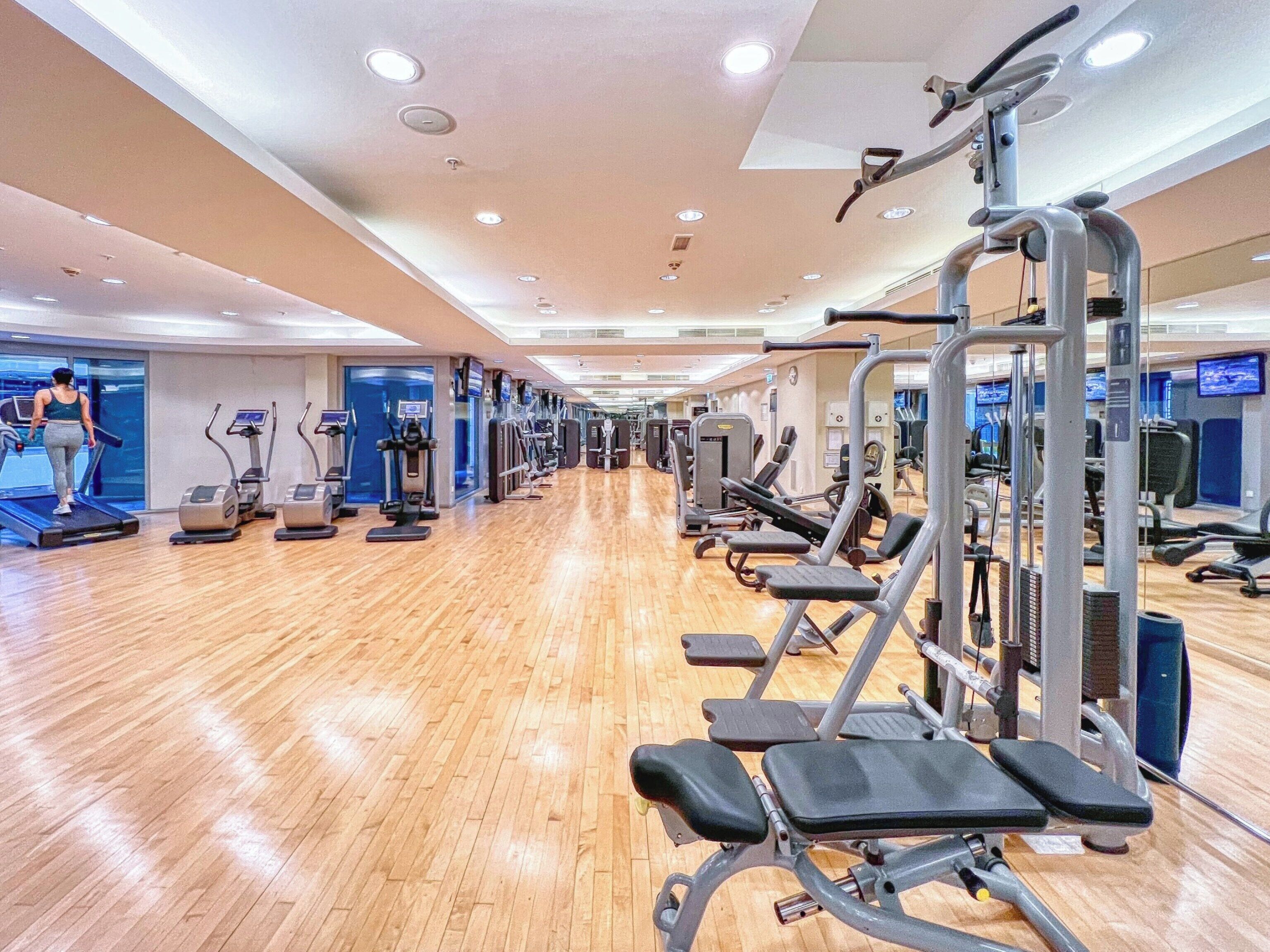 Ein Fitnessstudio mit Laufbändern, Crosstrainern und Kraftgeräten.