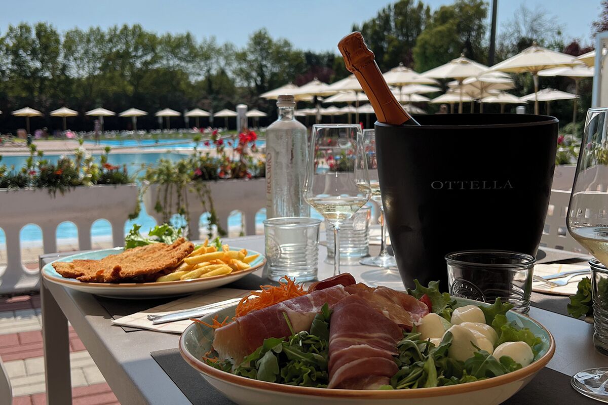 A dining table with a plate of food, a bottle of water, and a glass of wine.