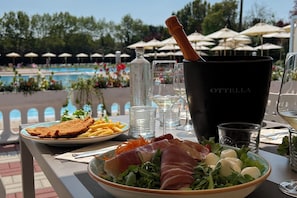 Una mesa de comedor con un plato de comida, una botella de agua y una copa de vino.