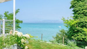 A coastal garden with a white pergola, lush greenery, and a clear view of the sea.
