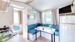 A compact kitchenette with a gas stove, a sink, and a small dining table with a blue cushioned bench.