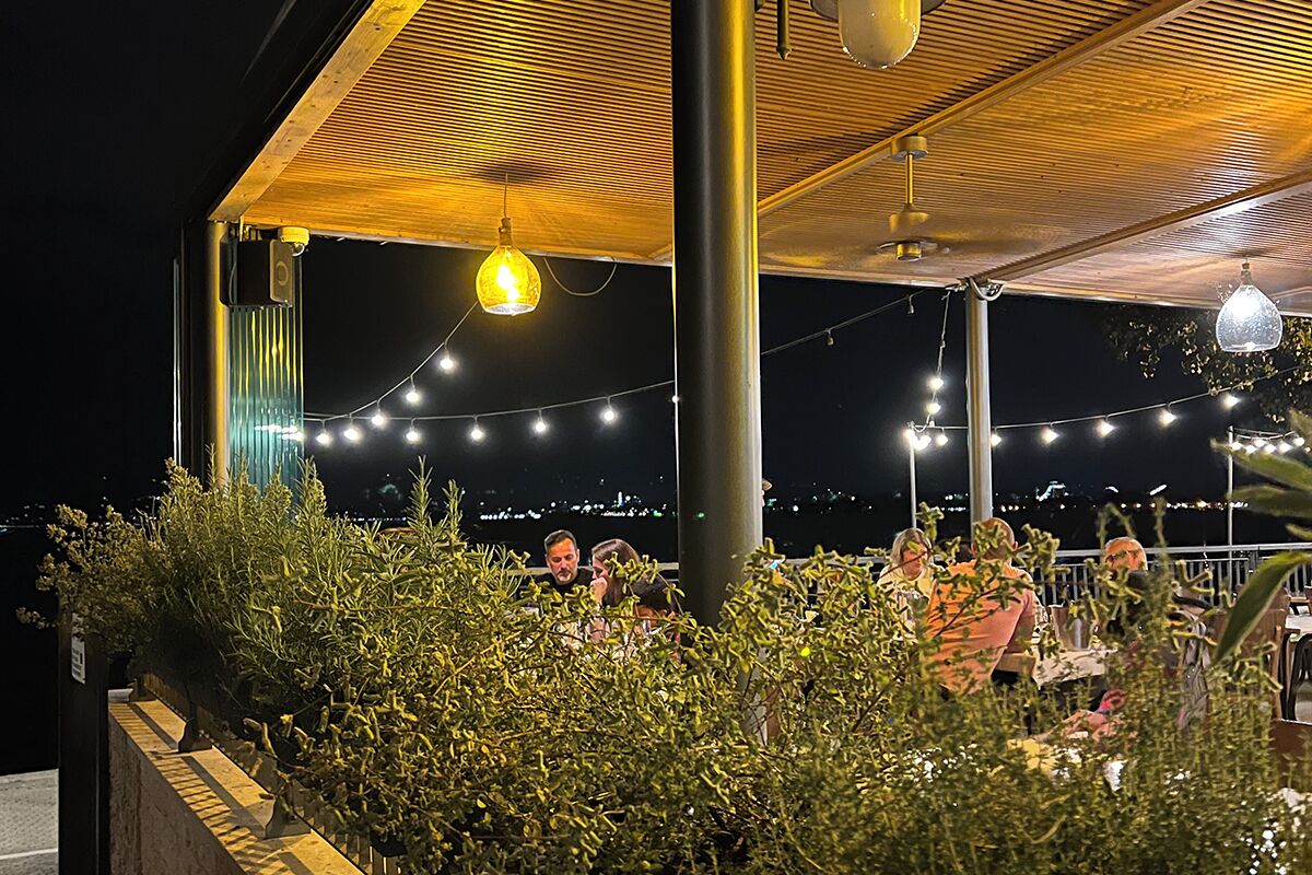 An outdoor dining area with string lights and a wooden pergola.