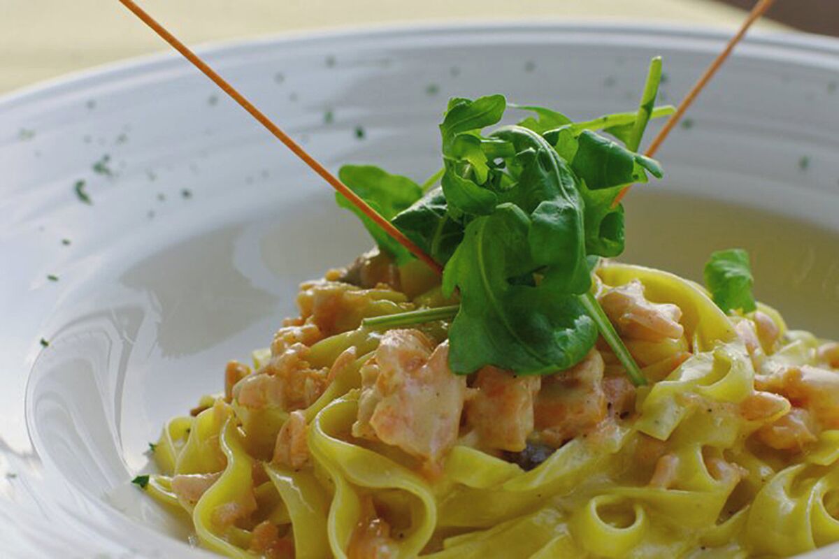 A plate of pasta with a creamy sauce and a garnish of greens.